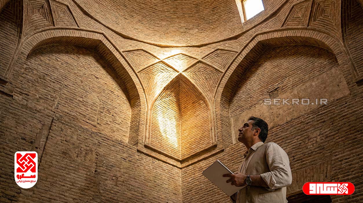 نمای داخلی و فنی از زیر گنبد آجری، تمرکز بر روی "سه‌کنج" (Squinch) و نحوه تبدیل پلان مربع به دایره، نورپردازی دراماتیک روی آجرها.
