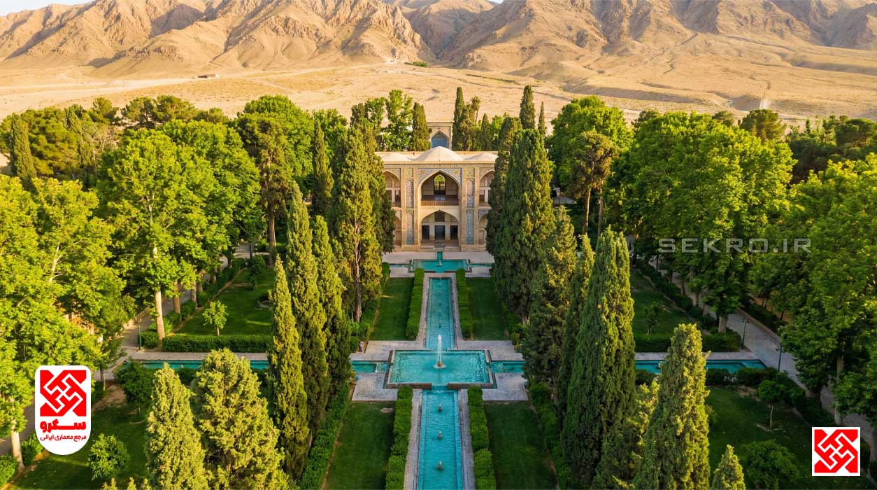 نمای هوایی متقارن از باغ ایرانی، جوی‌های آب فیروزه‌ای، کوشک مرکزی و درختان سرو منظم، نماد باغ ایرانی.